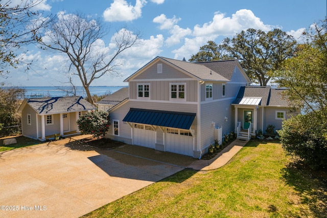 traditional-style house featuring a front yard, driveway, an attached garage, a shingled roof, and board and batten siding