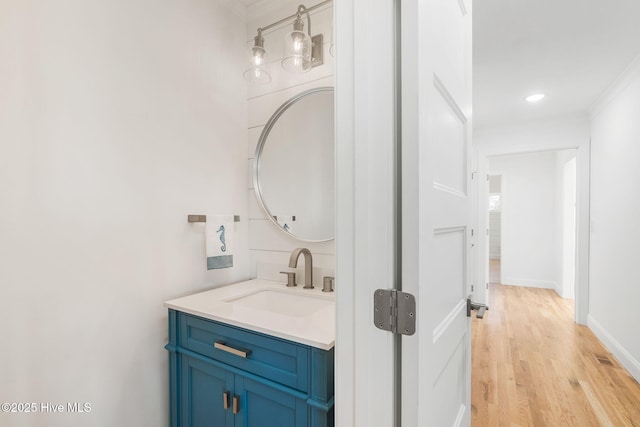 bathroom featuring ornamental molding, vanity, baseboards, and wood finished floors