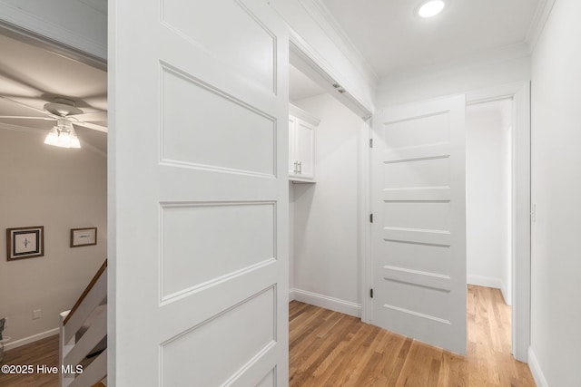 interior space with baseboards, light wood-style flooring, and crown molding