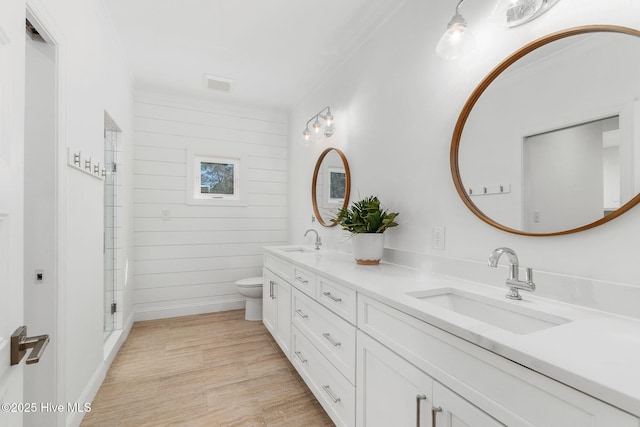 full bathroom with double vanity, toilet, wood finished floors, and a sink