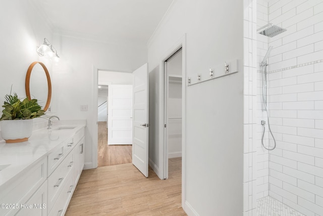 full bath with a walk in shower, double vanity, ornamental molding, wood finished floors, and a sink