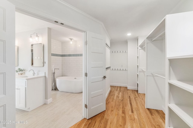 walk in closet with a sink, visible vents, and light wood-style flooring