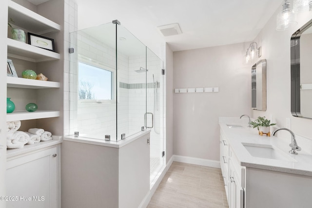 full bath featuring a sink, baseboards, a stall shower, and double vanity