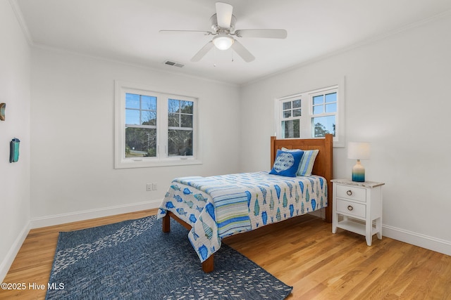 bedroom with baseboards, visible vents, ceiling fan, ornamental molding, and light wood-type flooring