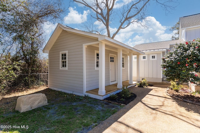 view of front of property with an outdoor structure, roof with shingles, and fence