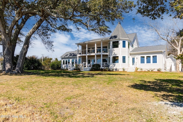 rear view of house with covered porch, a lawn, and a balcony