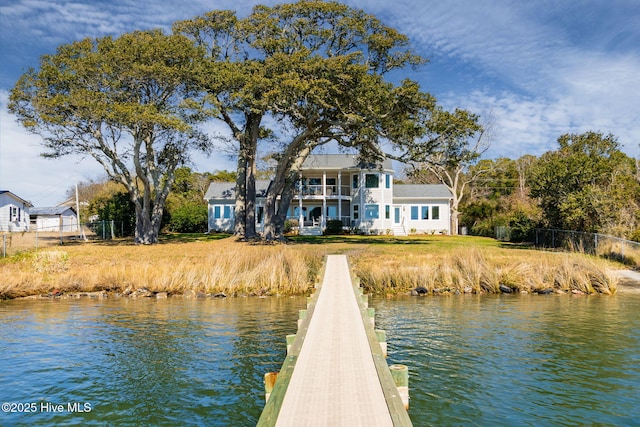 view of dock with a water view, a balcony, and fence