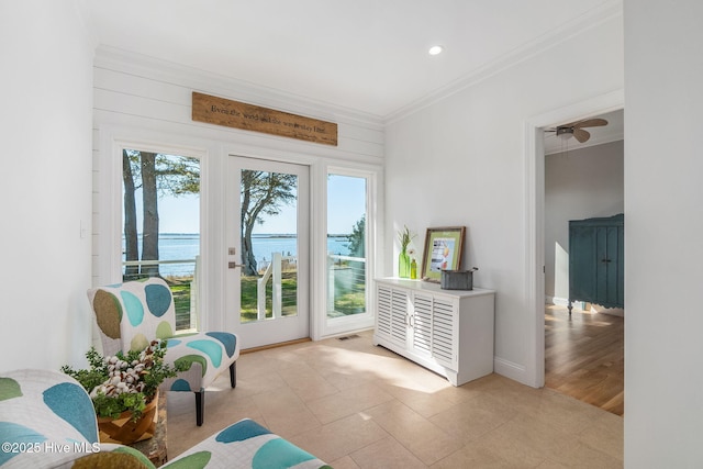 interior space featuring visible vents, a water view, crown molding, light tile patterned floors, and baseboards