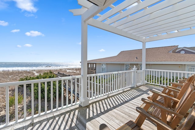 wooden terrace featuring a view of the beach and a pergola