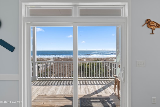 entryway with a wealth of natural light, a water view, wood finished floors, and a view of the beach