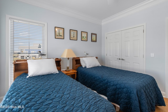 bedroom featuring a ceiling fan, wood finished floors, baseboards, a closet, and crown molding