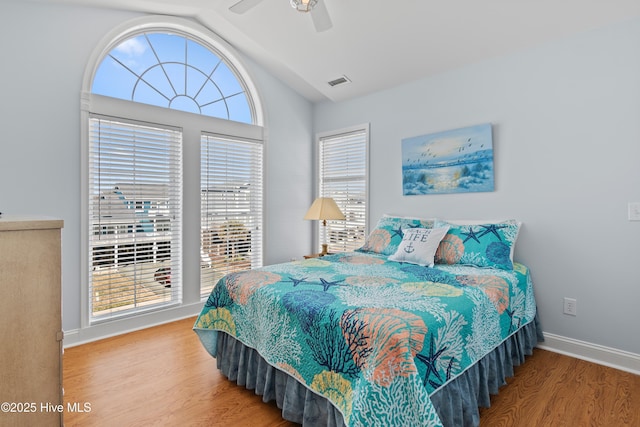 bedroom featuring visible vents, baseboards, wood finished floors, and vaulted ceiling