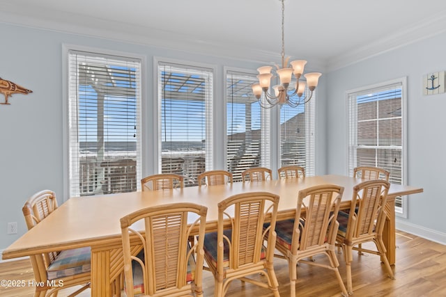 dining space featuring light wood-style flooring, a notable chandelier, baseboards, and ornamental molding