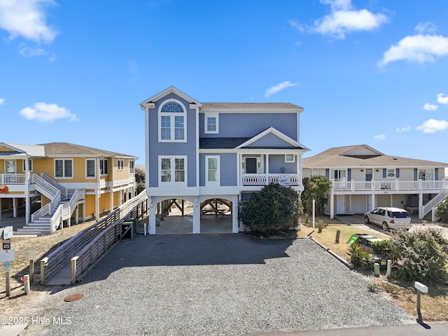 coastal home with a carport, a residential view, stairs, and gravel driveway