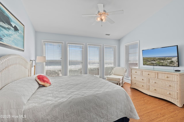 bedroom featuring vaulted ceiling, multiple windows, visible vents, and light wood-type flooring