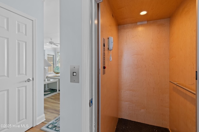 corridor with elevator, wood finished floors, and recessed lighting