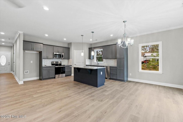 kitchen featuring tasteful backsplash, a kitchen island, light wood-style floors, appliances with stainless steel finishes, and baseboards