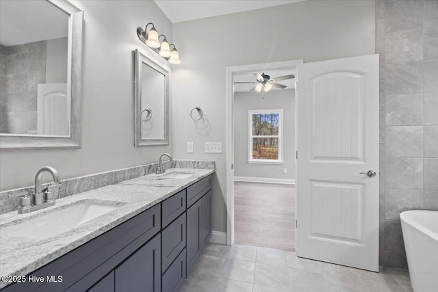 bathroom featuring tile patterned floors, double vanity, a freestanding bath, and a sink