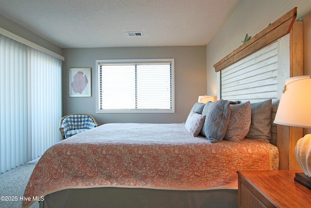 bedroom featuring visible vents, carpet flooring, and a textured ceiling