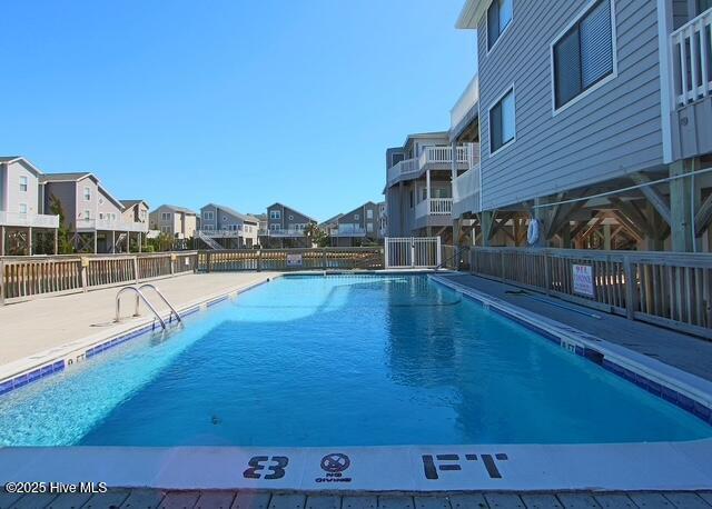 pool with a residential view, a patio, and fence