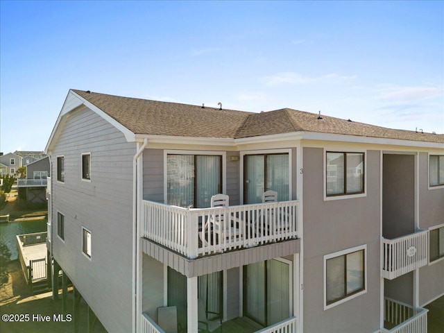 exterior space with stucco siding and a shingled roof