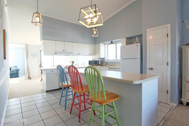 kitchen featuring light tile patterned floors, freestanding refrigerator, a towering ceiling, stainless steel microwave, and light colored carpet