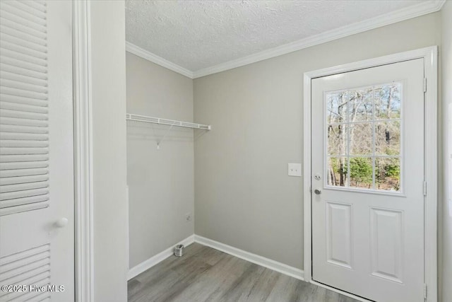 laundry room with a textured ceiling, wood finished floors, crown molding, baseboards, and laundry area