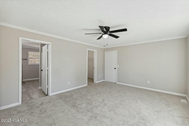 unfurnished bedroom with a spacious closet, carpet flooring, and crown molding