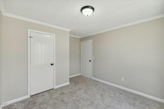 unfurnished bedroom featuring crown molding, baseboards, carpet floors, and a textured ceiling