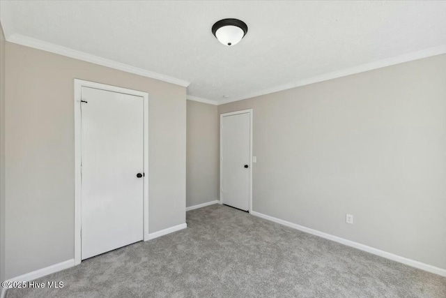 unfurnished bedroom featuring crown molding, carpet flooring, and baseboards