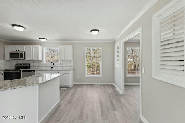 kitchen featuring a sink, tasteful backsplash, white cabinetry, stainless steel appliances, and crown molding