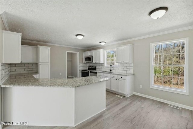 kitchen with light stone countertops, visible vents, light wood finished floors, a sink, and appliances with stainless steel finishes