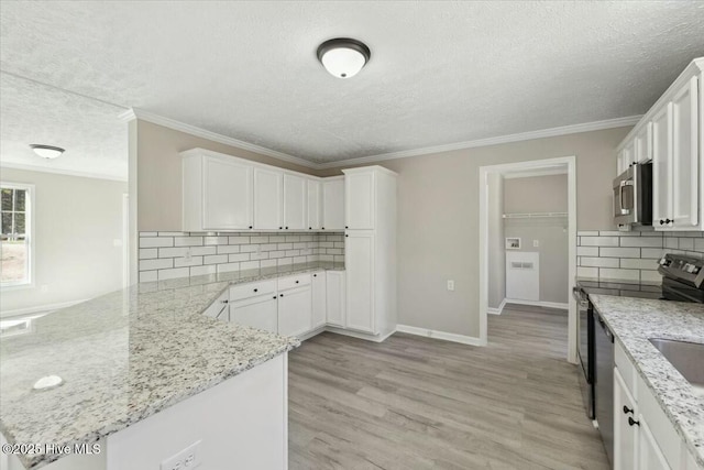 kitchen with a peninsula, stainless steel appliances, white cabinets, crown molding, and light wood-type flooring