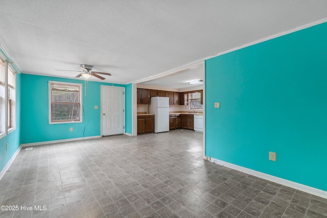 unfurnished living room with baseboards, ornamental molding, tile patterned floors, a textured ceiling, and a ceiling fan