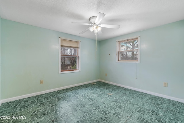 empty room featuring a textured ceiling, baseboards, and a ceiling fan