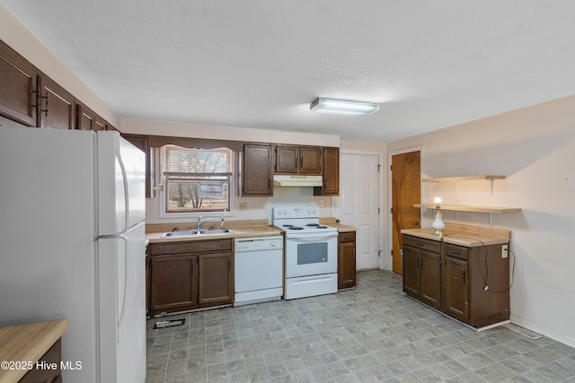 kitchen with under cabinet range hood, white appliances, light countertops, and a sink