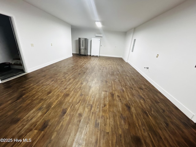 unfurnished living room featuring dark wood-type flooring and baseboards