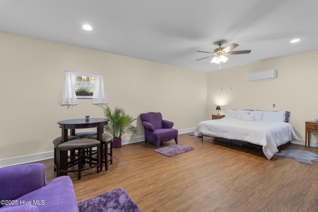 bedroom with an AC wall unit, wood finished floors, baseboards, recessed lighting, and ceiling fan