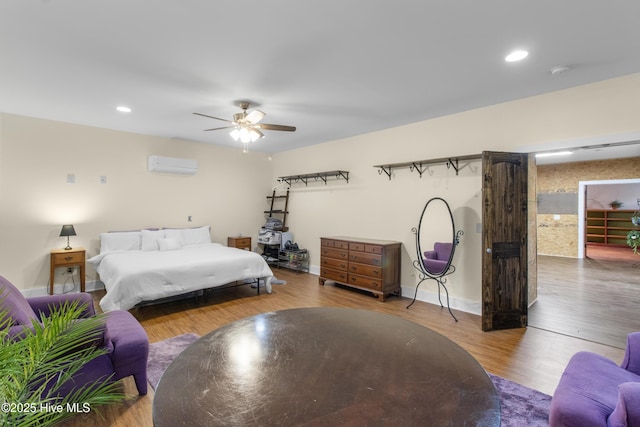 bedroom with a wall mounted air conditioner, wood finished floors, ceiling fan, recessed lighting, and baseboards
