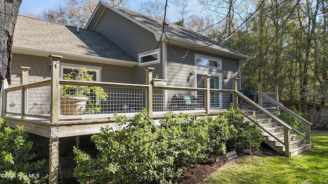 rear view of property with a shingled roof, a wooden deck, and stairway