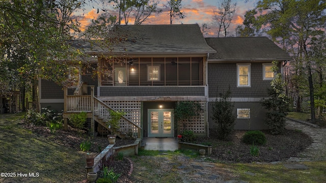 view of front of house with french doors, a sunroom, a shingled roof, and stairway