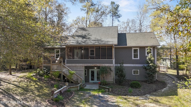 rear view of property featuring french doors, a sunroom, and roof with shingles