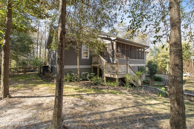 back of house featuring a sunroom, stairway, and fence