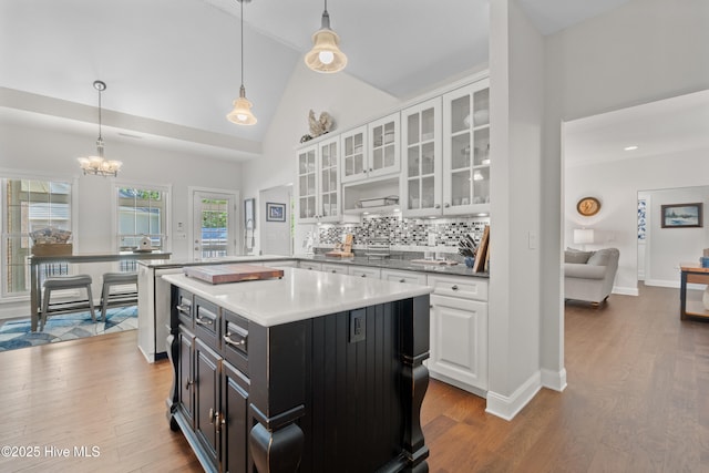 kitchen with wood finished floors, pendant lighting, white cabinetry, dark cabinets, and backsplash