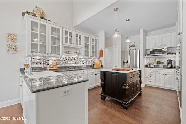 kitchen with a sink, stainless steel appliances, wood finished floors, and white cabinets