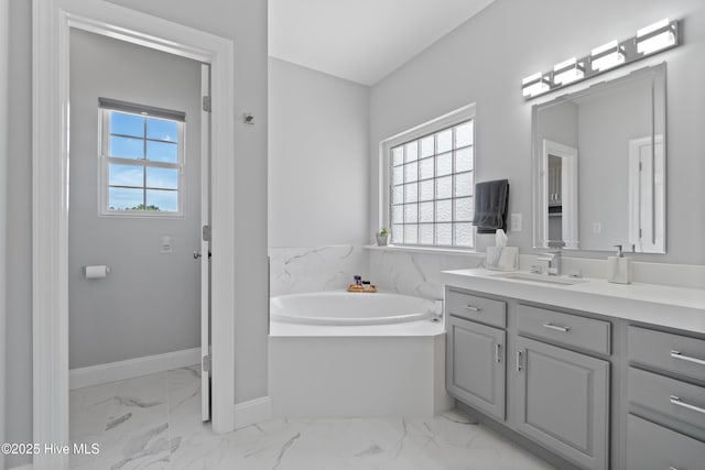 bathroom featuring vanity, a bath, baseboards, and marble finish floor