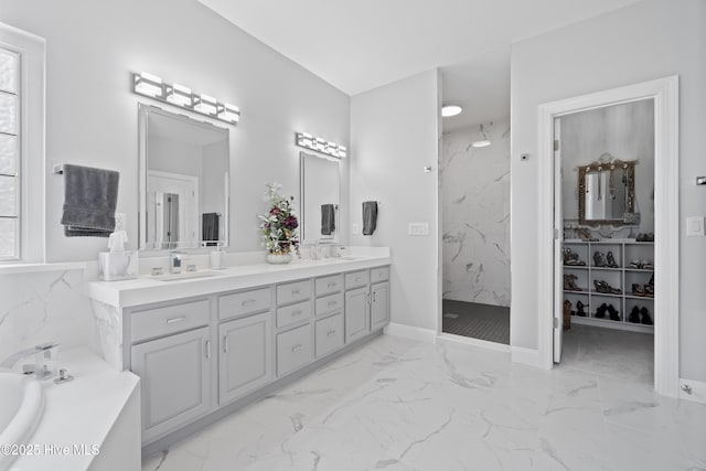 bathroom featuring a marble finish shower, marble finish floor, a garden tub, and a sink