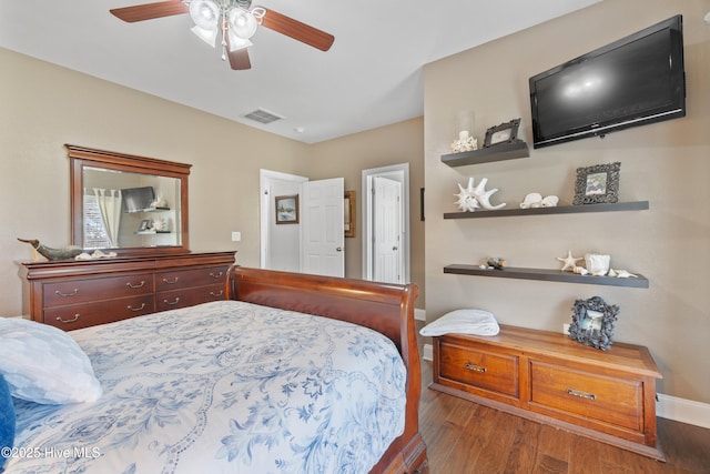 bedroom featuring a ceiling fan, wood finished floors, visible vents, and baseboards