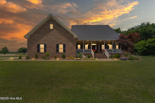 view of front of home featuring brick siding, a porch, and a front lawn