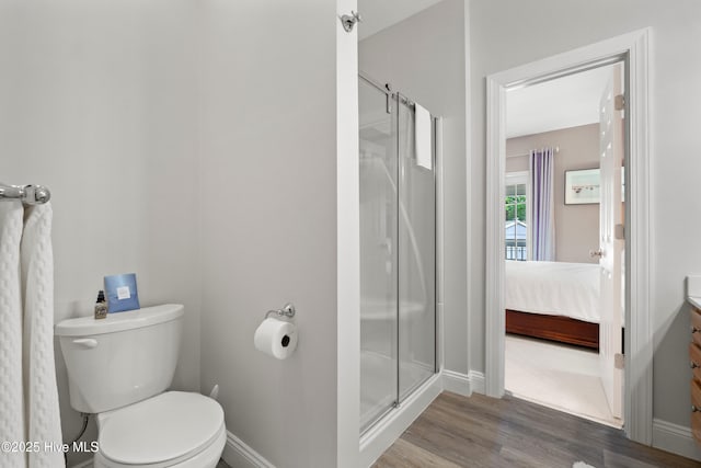 full bath featuring toilet, ensuite bathroom, wood finished floors, a shower stall, and baseboards